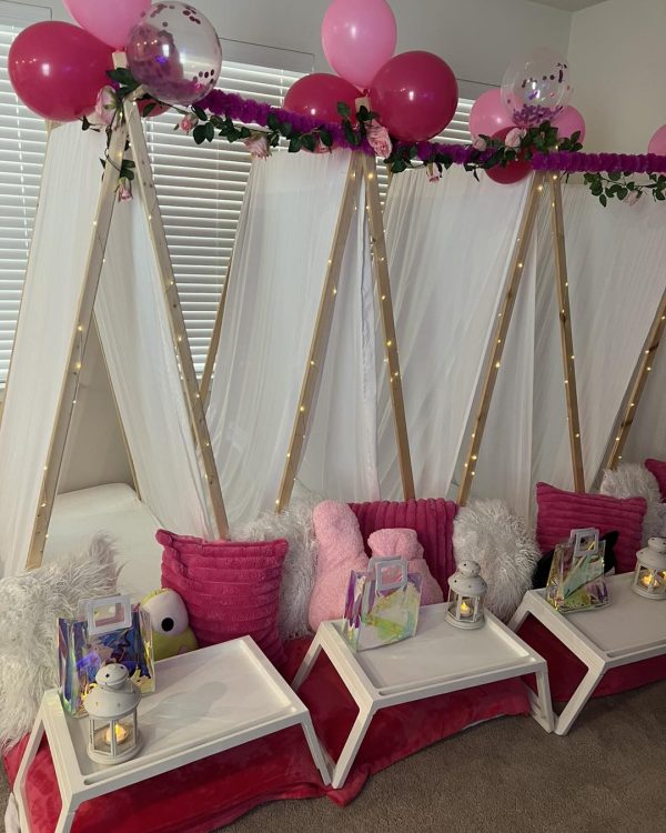 A pink teepee tent embellished with balloons and decorations.