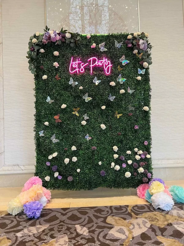 A green wall adorned with enchanting flowers and a sign that reads "life party.